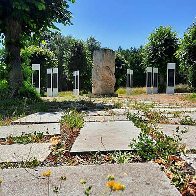 Unebener Weg zum Denkmal und den Namenstafeln auf dem Friedhof 
